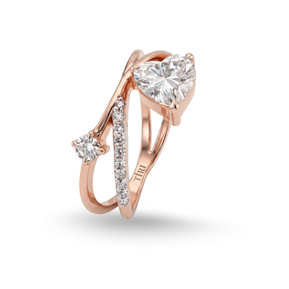 Tiri crossover heart diamond ring featuring intertwined gold bands with sparkling diamonds on a white background.