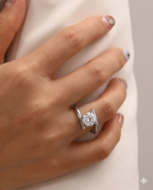 Close-up of a hand wearing a silver ring with a diamond on a neutral background