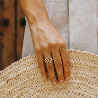 Hand wearing a gold ring on a woven surface