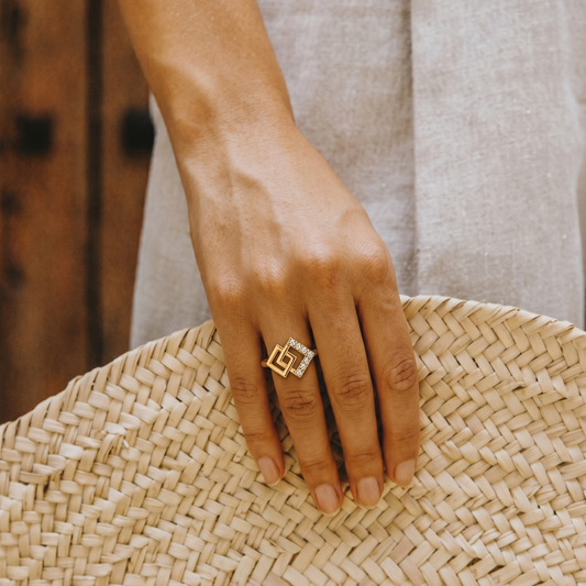 Hand wearing a gold ring on a woven surface
