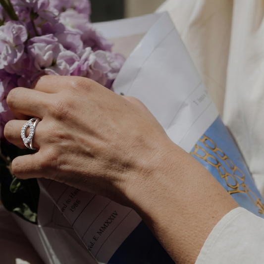 Person holding a bouquet of flowers and a magazine with a decorative ribbon.