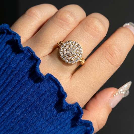 Close-up of a hand wearing a gold ring with diamonds, against a dark background.
