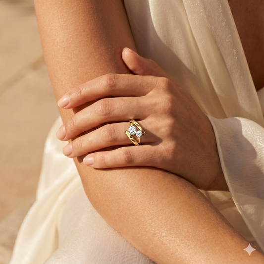 Gold ring with a diamond on a person's finger against a neutral background