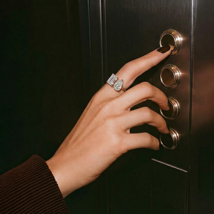 Hand pressing an elevator button with a diamond ring on a dark elevator panel.