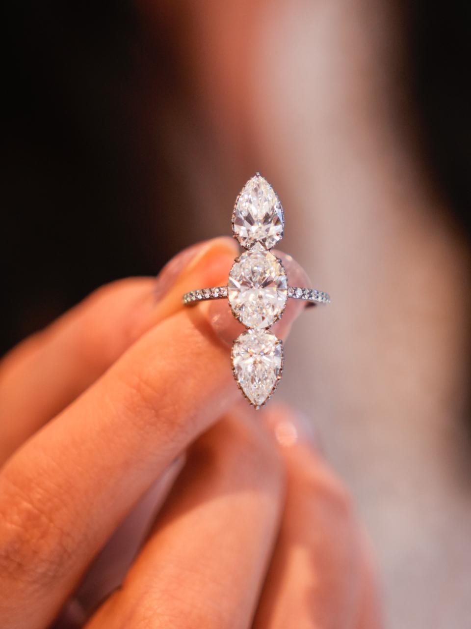 Vintage style three-stone anniversary ring featuring oval and pear cut diamonds, platinum setting