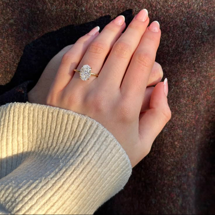 Hand wearing a diamond ring on a textured surface