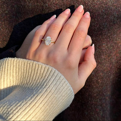 Hand wearing a diamond ring on a textured surface