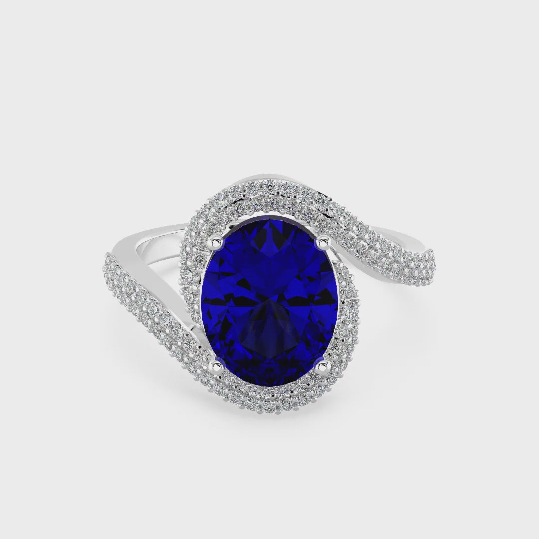 Elegant white gold ring featuring an oval blue gemstone with a twisted diamond-pavé band, photographed on a white background.