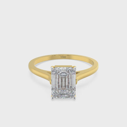 Emerald-cut solitaire diamond ring set in yellow gold.