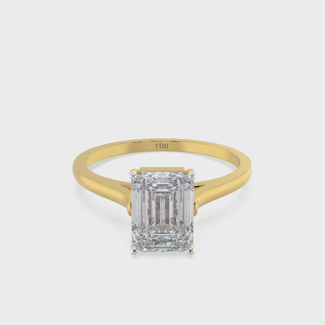 Emerald-cut solitaire diamond ring set in yellow gold.