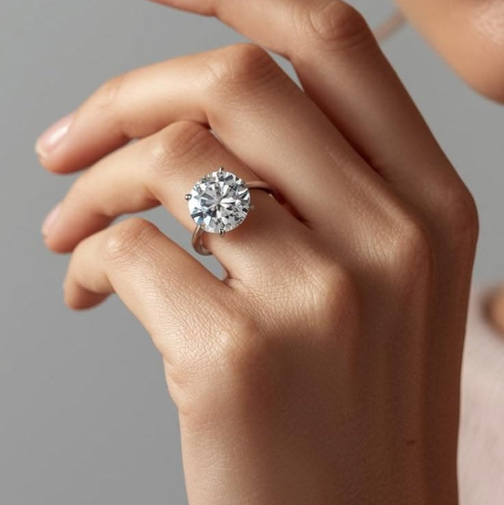 Close-up of a hand wearing a diamond ring on a neutral background