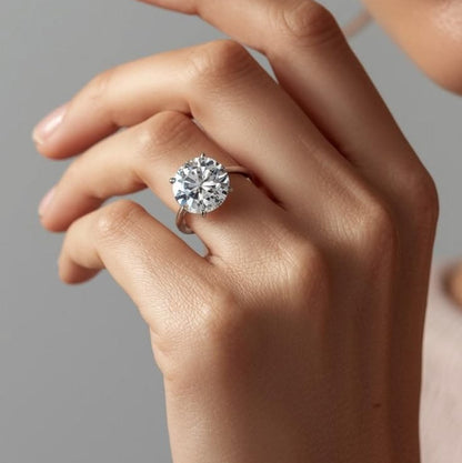 Close-up of a hand wearing a diamond ring on a neutral background